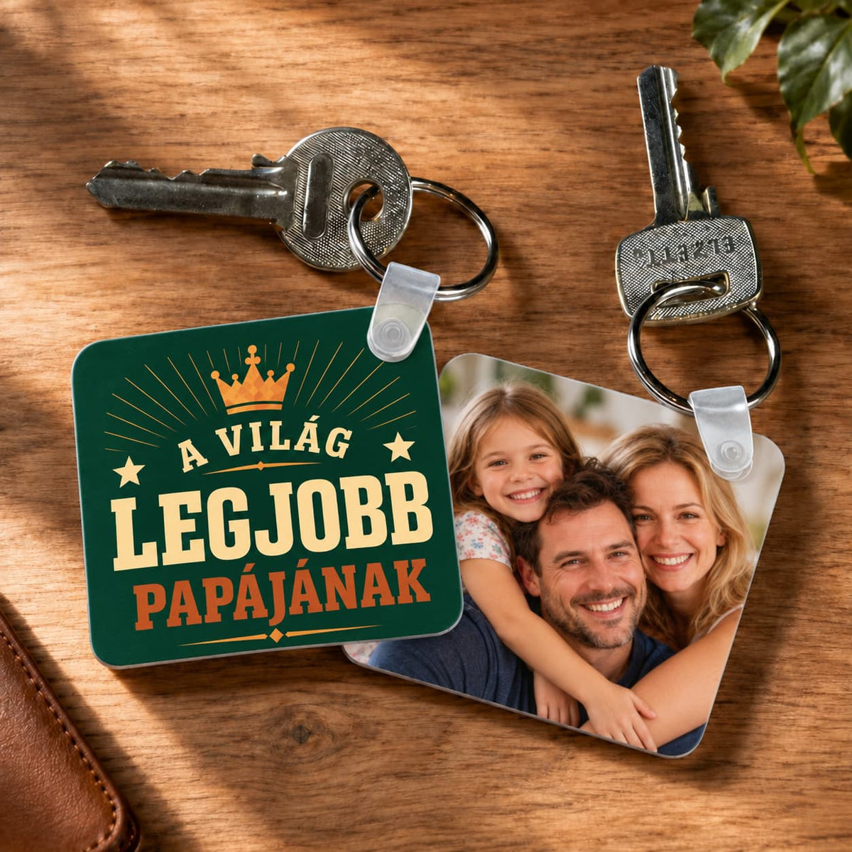 Kétoldalas műanyag fényképes kulcstartó, balra „A világ legjobb papájának” grafikával, jobbra családi fotóval, fa háttéren.