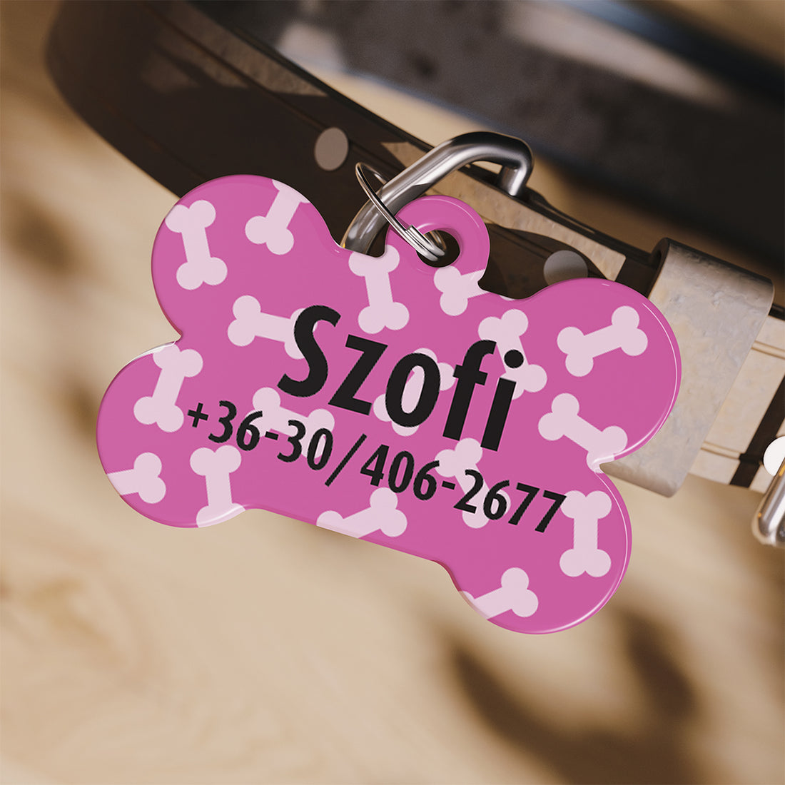 Rózsaszín, fehér csontmintás, csont alakú kutyabiléta névvel és telefonszámmal, nyakörvre akasztva