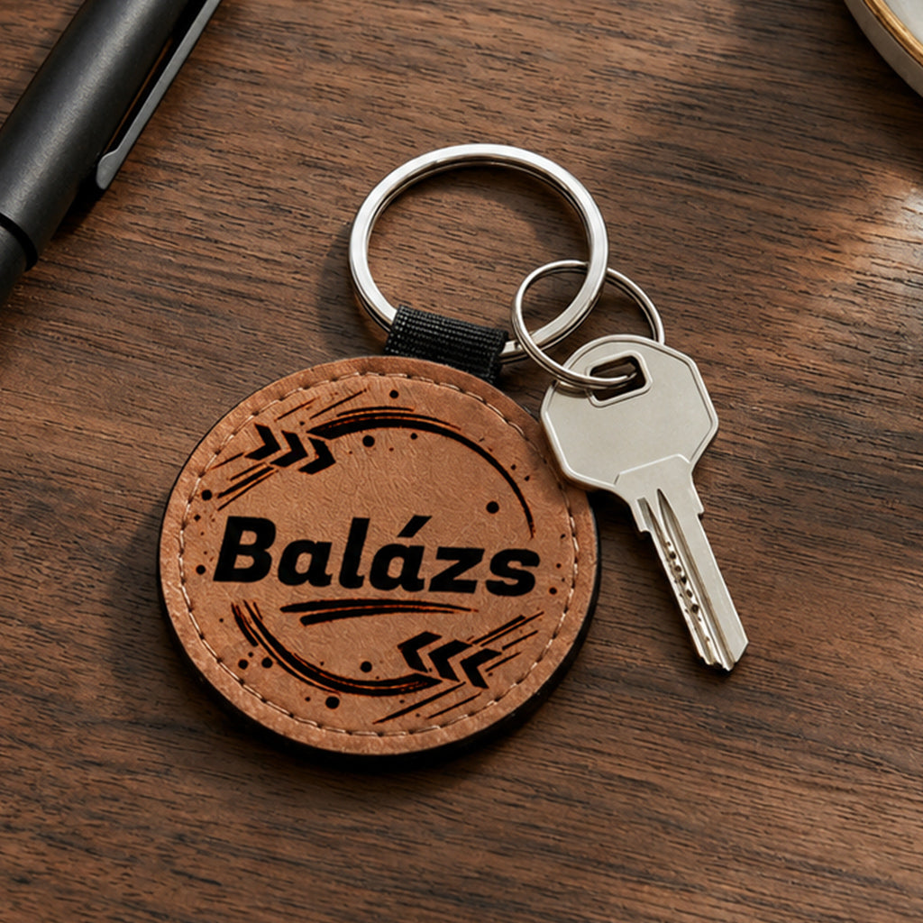 Egyedi névreszóló barna színű bőr kulcstartó saját névvel és modern grafikával, krómozott fém kulcskarikával és kulccsal, fa asztali környezetben fotózva. Praktikus és személyes ajándék férfiaknak és nőknek.