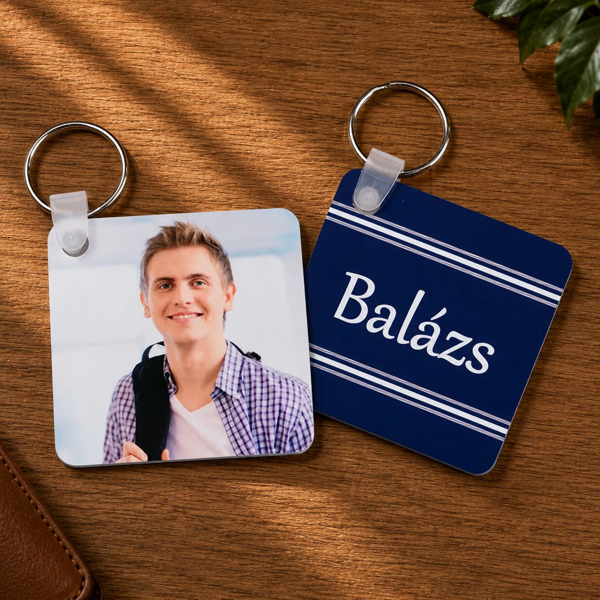 „Balázs” feliratú és férfi portréjával készült négyzet alakú egyedi fényképes kulcstartók, meleg fa háttéren.