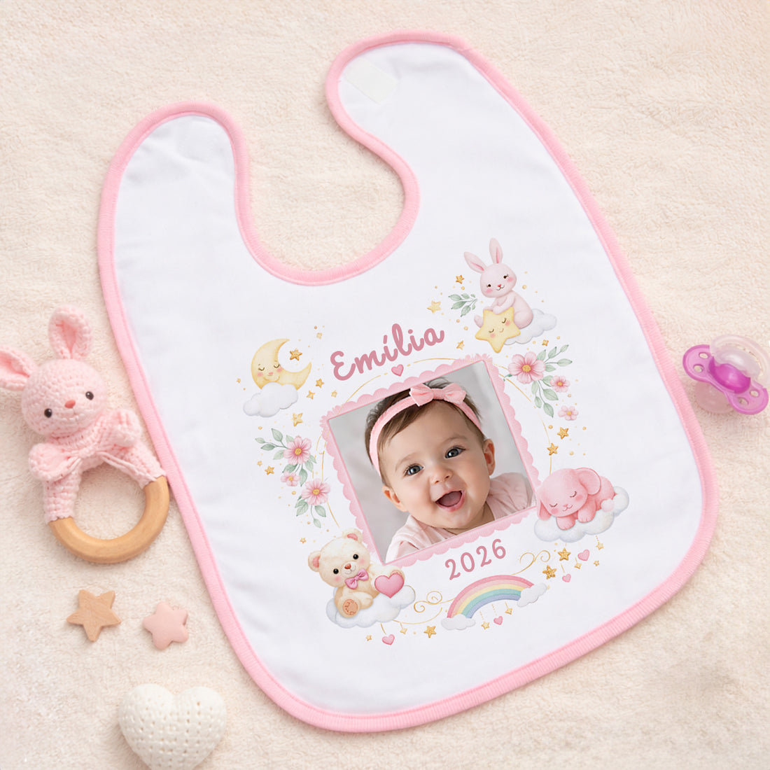 Egyedi névre szóló fényképes baba előke rózsaszín szegéllyel, pasztell nyuszis és szivárványos grafikával, cserélhető névvel, évszámmal és fotóval.
