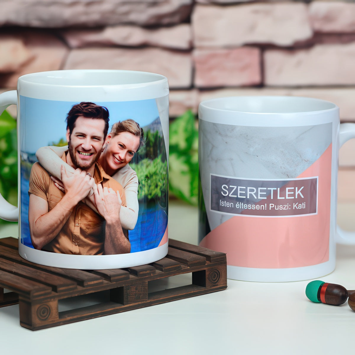 Két fényképes bögre, az egyiken egy ölelkező pár fotója, a másikon márvány és rózsaszín mintán Szeretlek felirat
